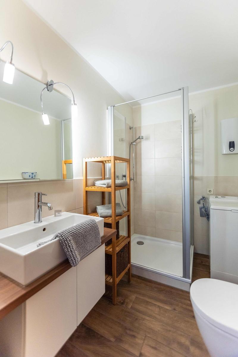 Waschbecken mit Spiegel, Holzregalen und moderner Armaturen.