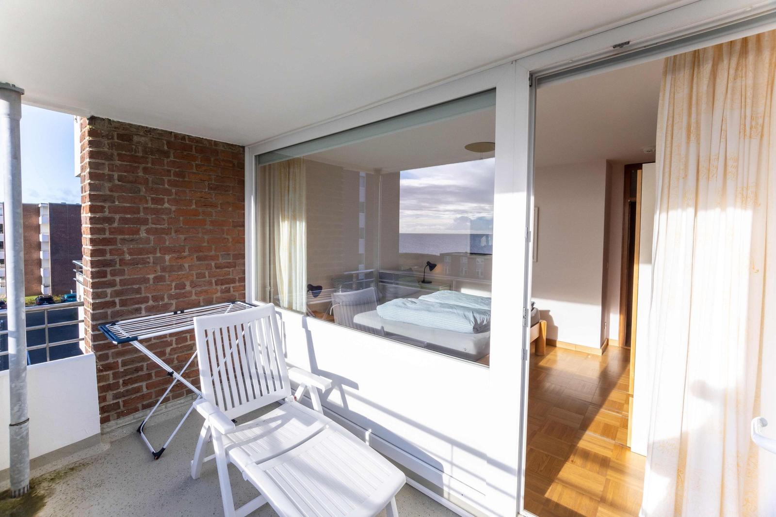Terrasse mit weißem Liegestuhl und Wäscheständer vor Backsteinmauer