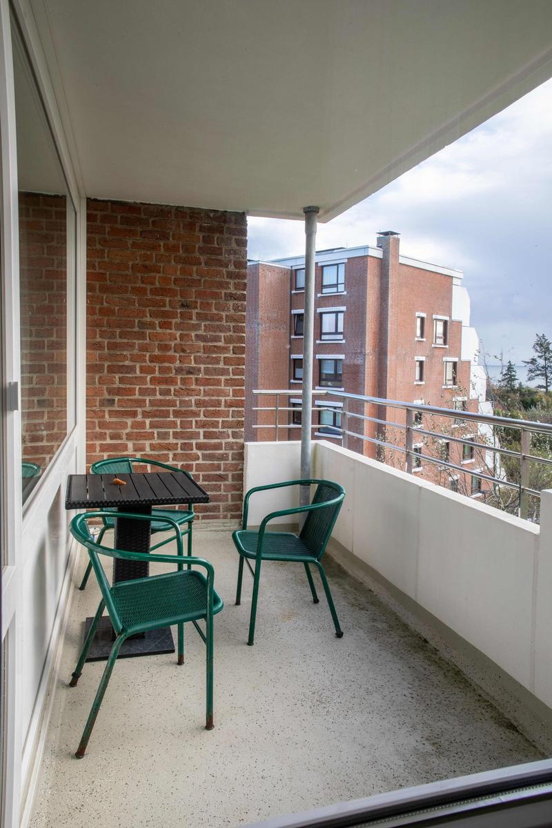 Essbereich mit Holztisch, Stühlen und einem alten Schrank. Große Fenster mit Blick nach draußen.