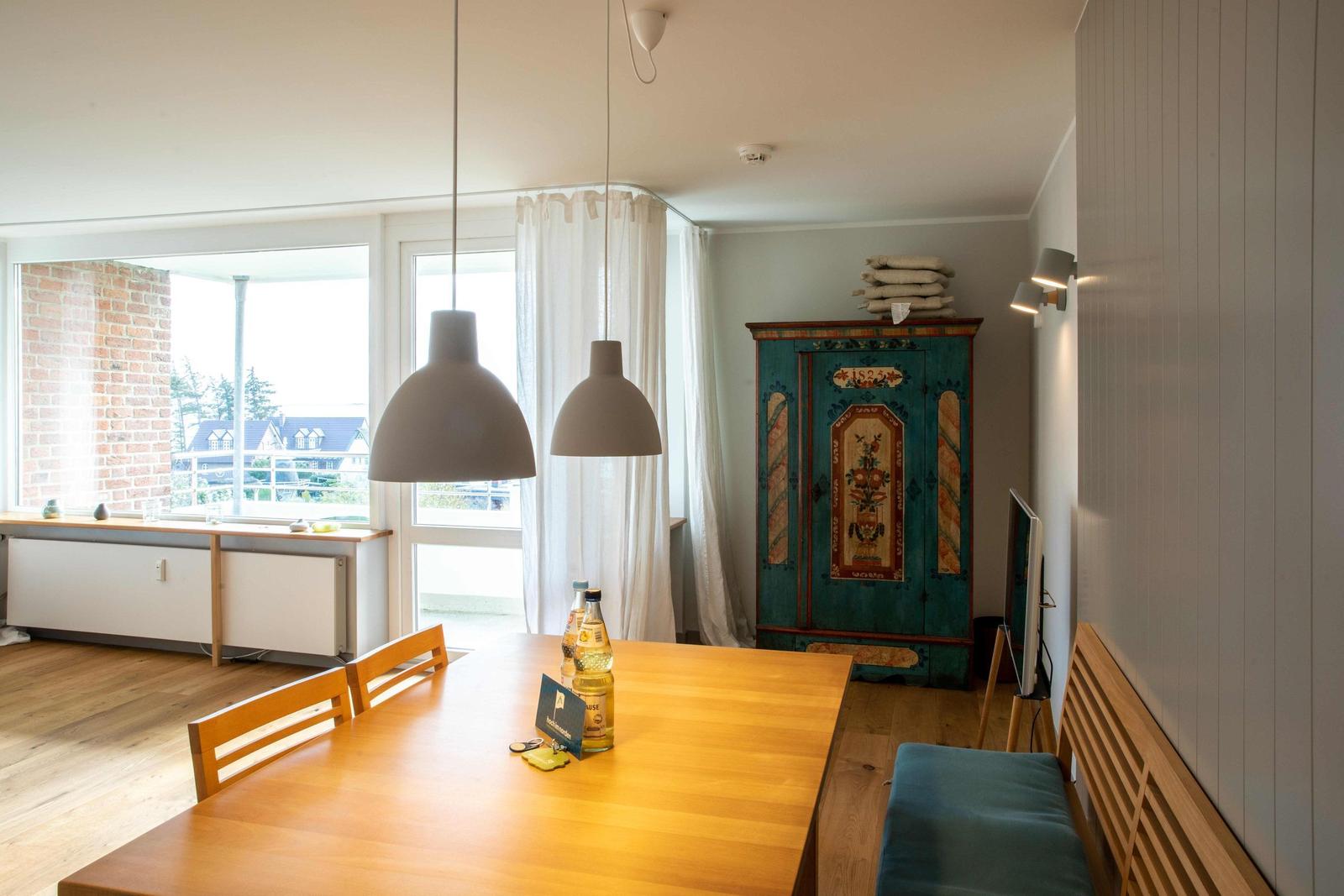 Esszimmer mit Holztisch, Bänken und einem alten Schrank. An der Wand hängt ein Fernseher.