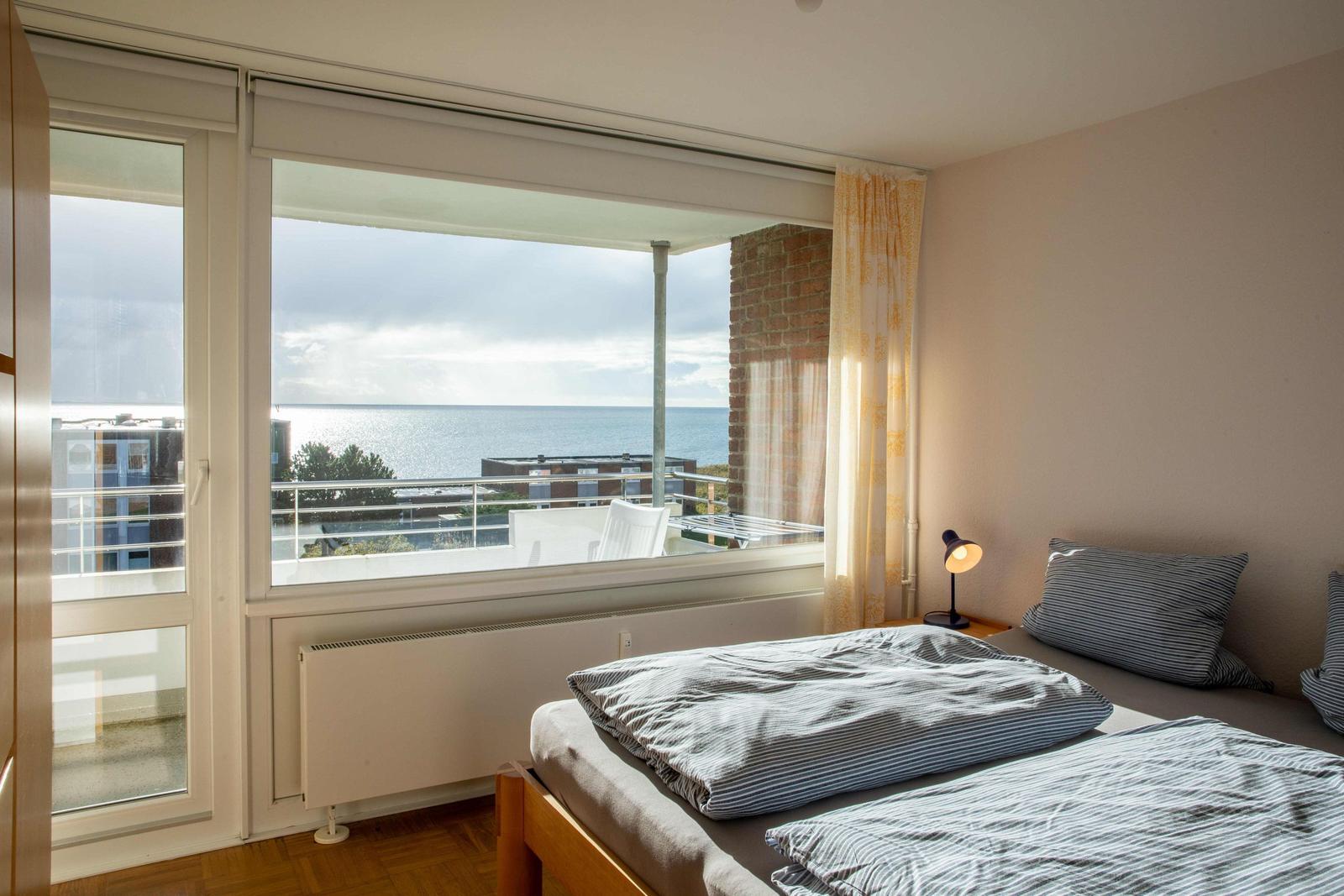 Schlafzimmer mit Bett, Kleiderschrank und Wandbild.