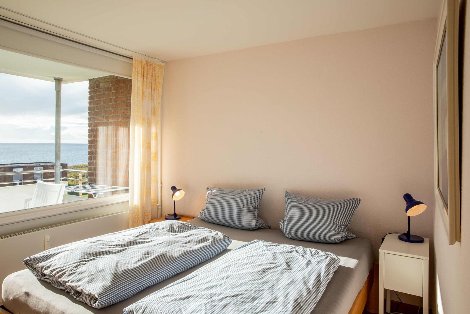 Ein Schlafzimmer mit Bett, zwei Nachttischen und einer Wanddekoration.