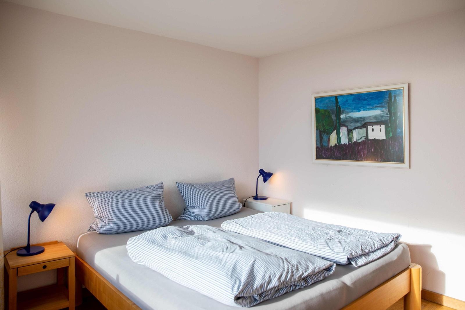 Schlafzimmer mit Doppelbett, Fenster und Wanddekoration.