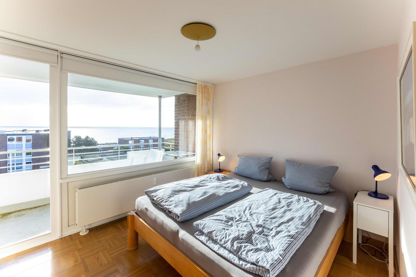 Wohnung mit Balkon in Mehrfamilienhaus, umgeben von Grünflächen und Blumen.