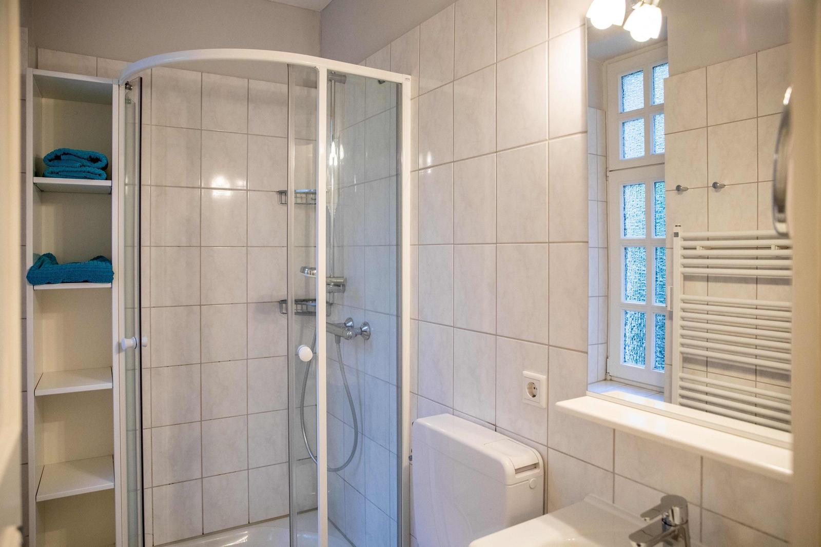 Wohnzimmer mit Sofa, Stuhl und Tisch. Fenster mit Markisen. Wandbild und Beleuchtung.