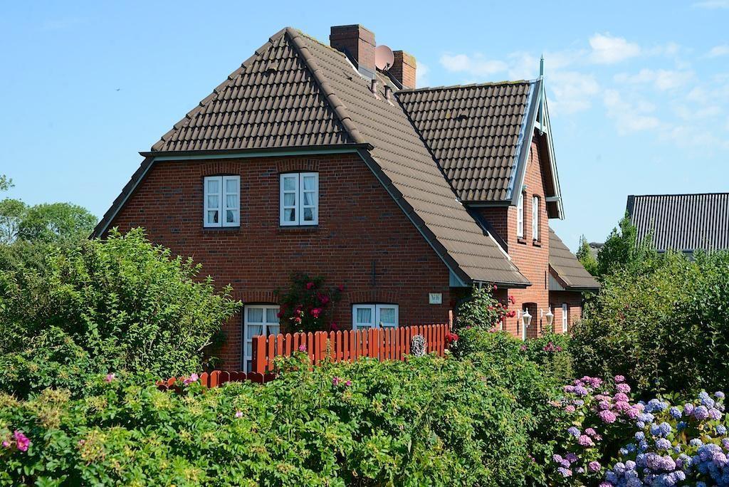 Rotes Backsteinhaus mit Garten, Sitzgelegenheit und Baum. Hinterhof mit Pavillon.