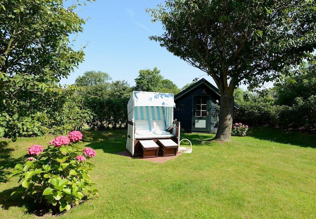 Wohnzimmer mit Sofa, Sesseln und Fenstern mit Blick auf Garten.