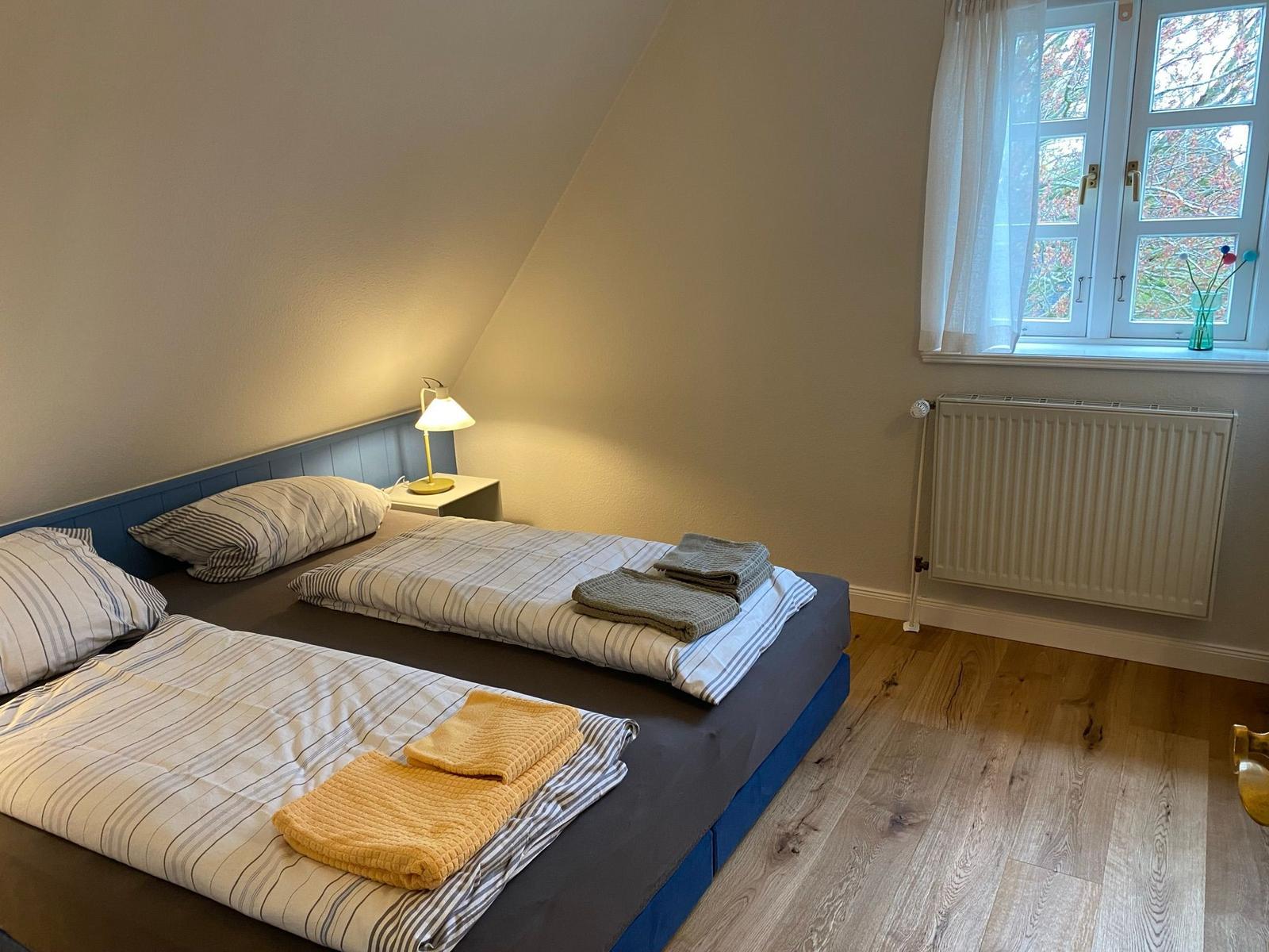 Schlafzimmer mit Dachschrägen, blauer Wand, Sofa und Stuhl.