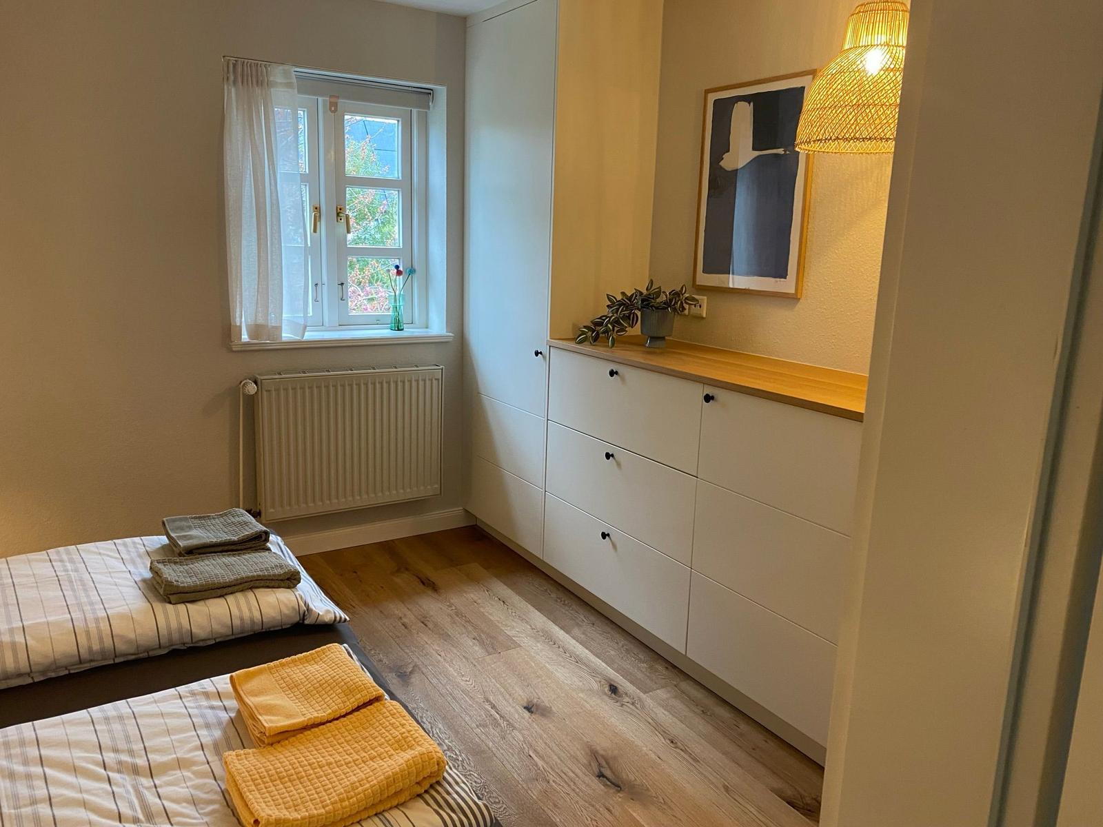 Dachgeschosszimmer mit Sitzgelegenheit, Tisch und Lampe. Holzboden und blaue Wand.