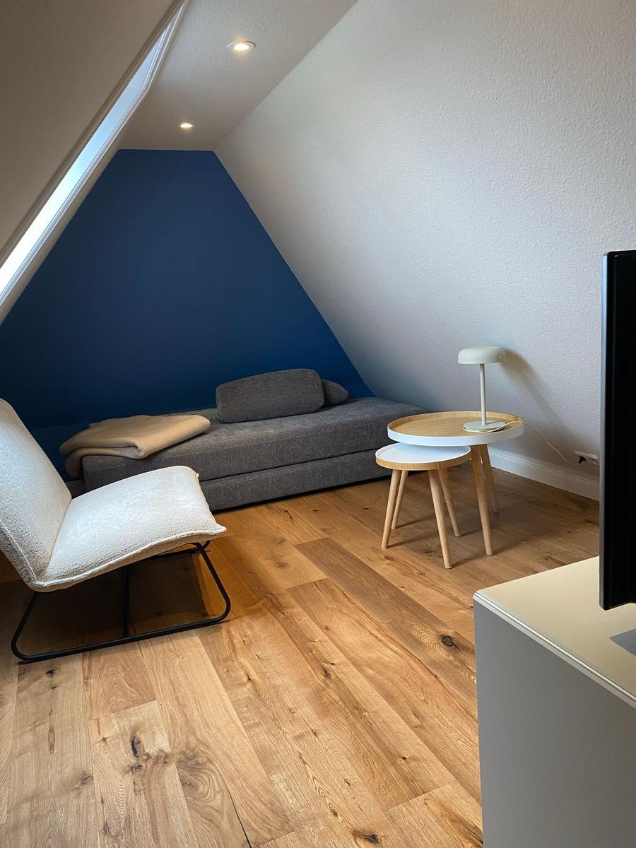 Runder Tisch mit vier grünen Stühlen und Decke. Hängelampe über dem Tisch.
