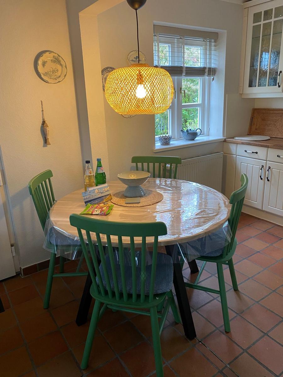 Wohnzimmer mit Ecksofa, zwei Tischen und Fenstern mit Jalousien.