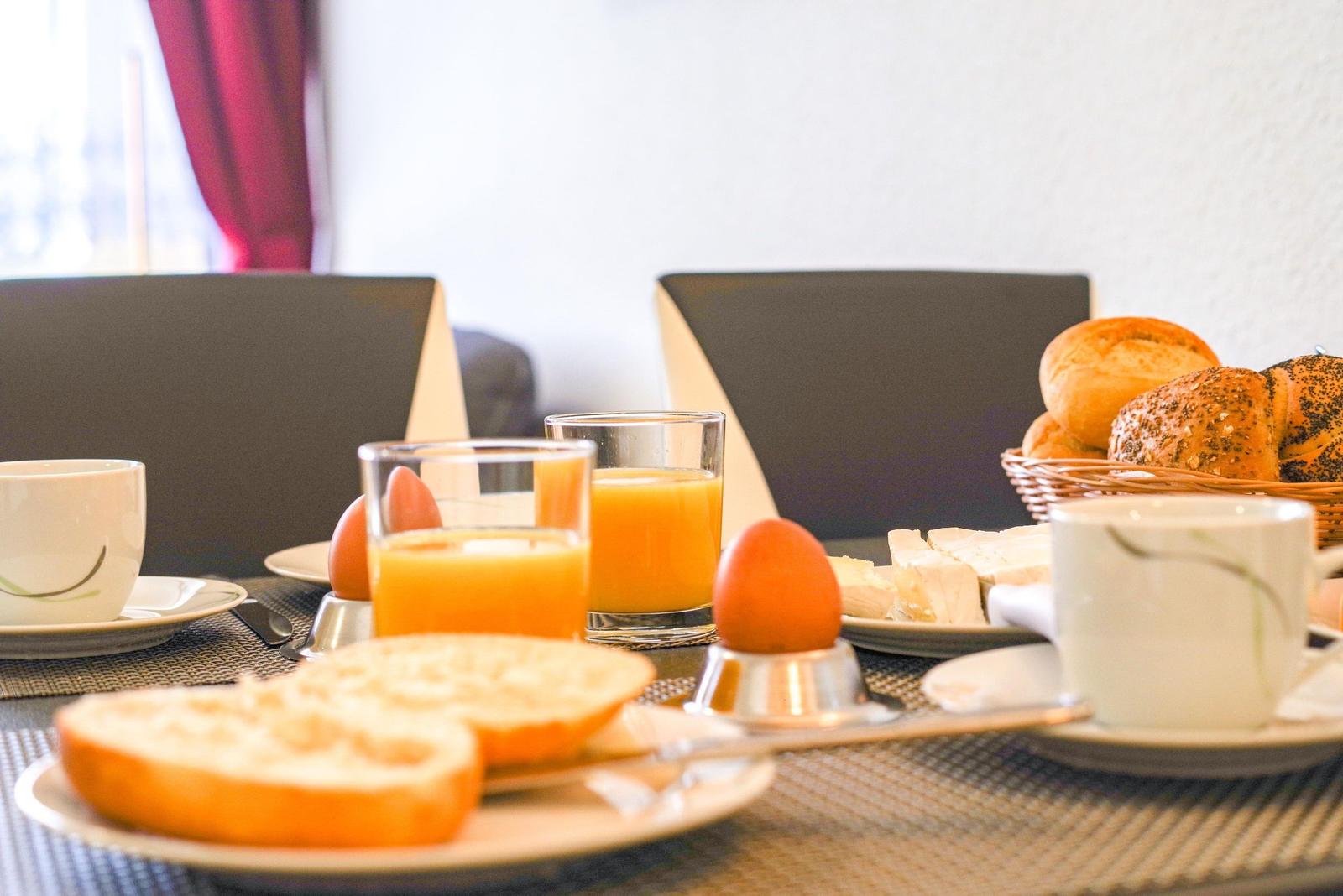 Frühstückstablett mit Brot, Eiern, Orangensaft und Käse.