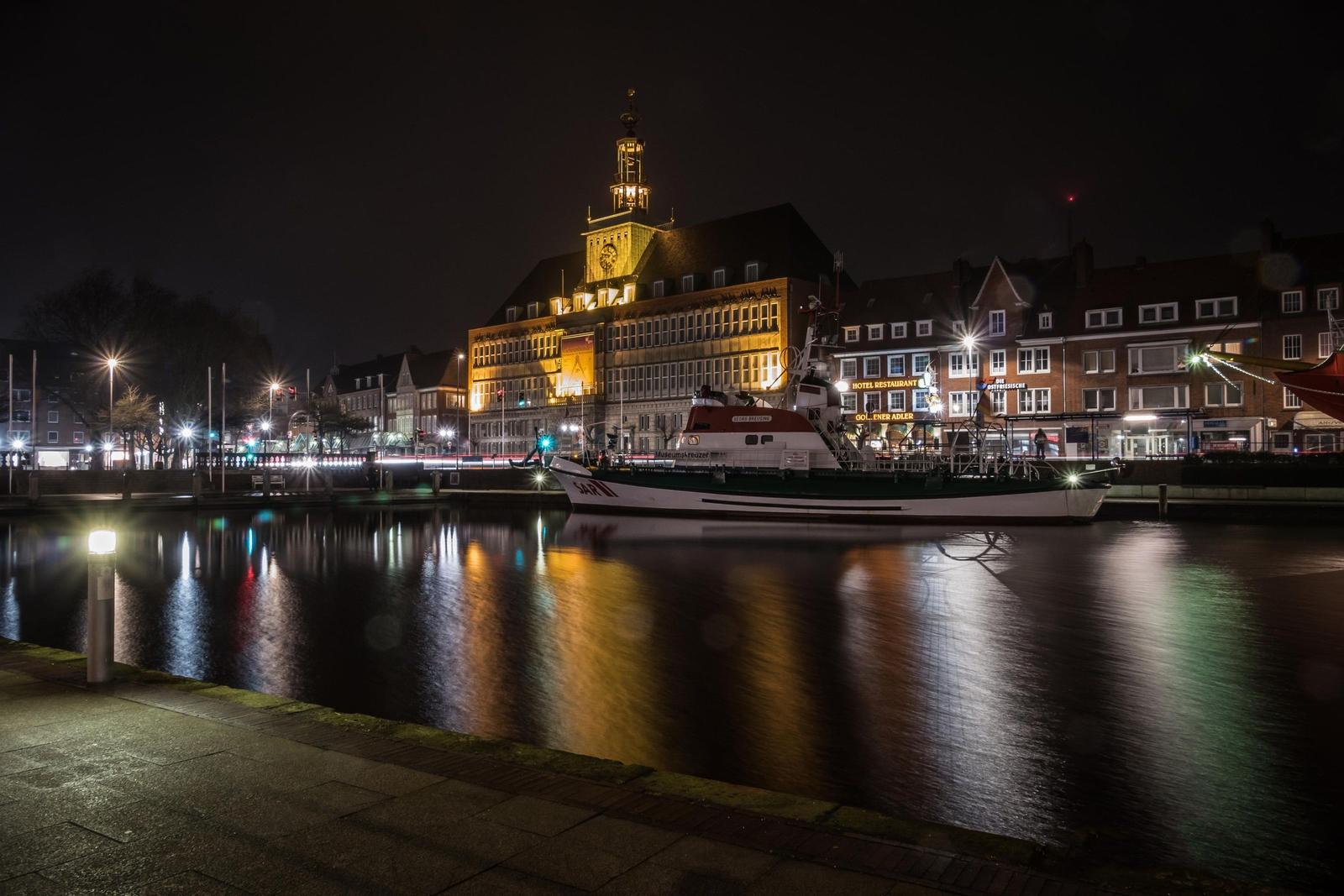 Hafen mit vielen Fischerbooten und grüner Uferpromenade.