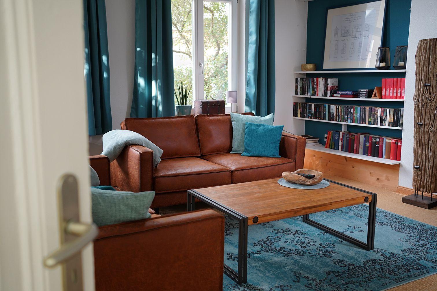 Ein Raum mit Bücherregalen an der Wand, einem Sofa und Vorhängen.
