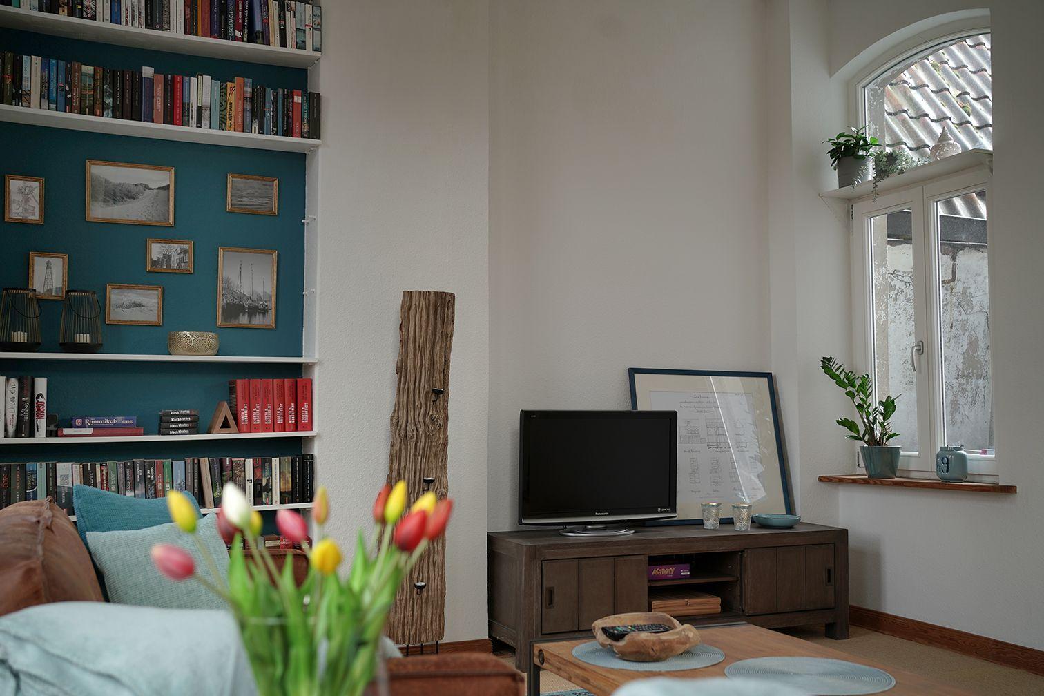 Ein braunes Ledersofa mit einer hellen Decke und Tulpen im Hintergrund.