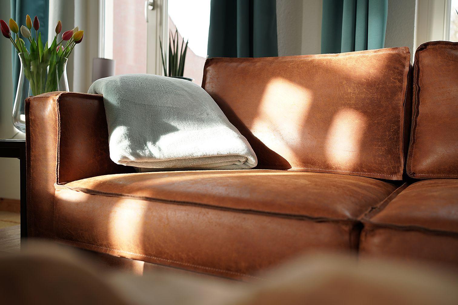 Schlafzimmer mit Bett, Nachttisch und Wandlampen. Fenster mit Vorhang und Dekoration.