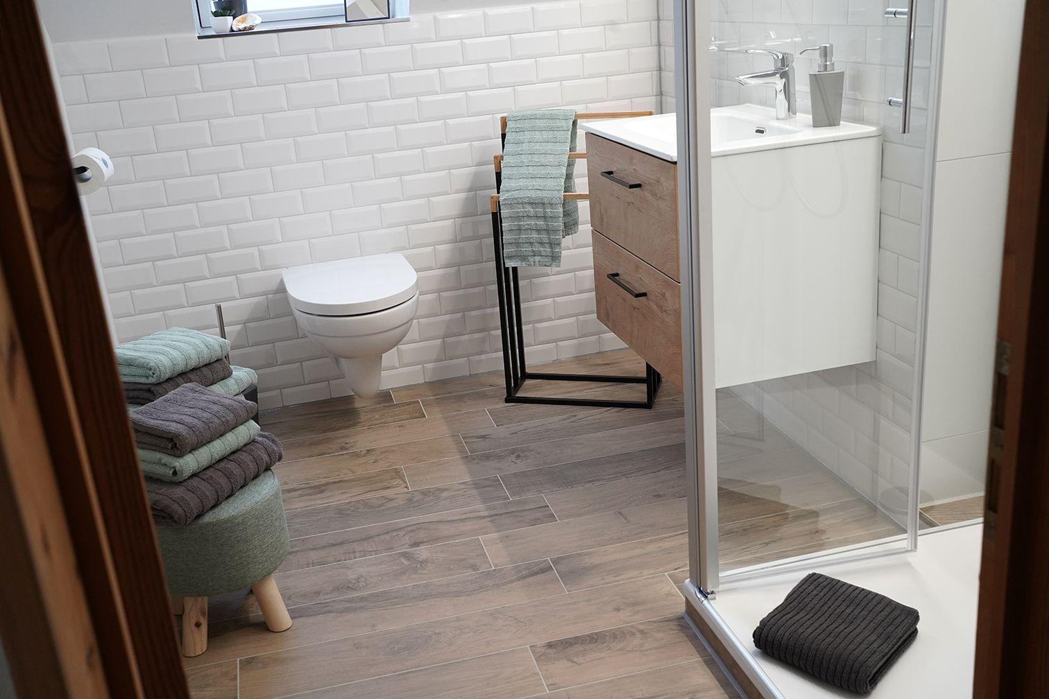 Badezimmer mit beleuchtetem Spiegel, Pflanze und Schale auf der Ablage.