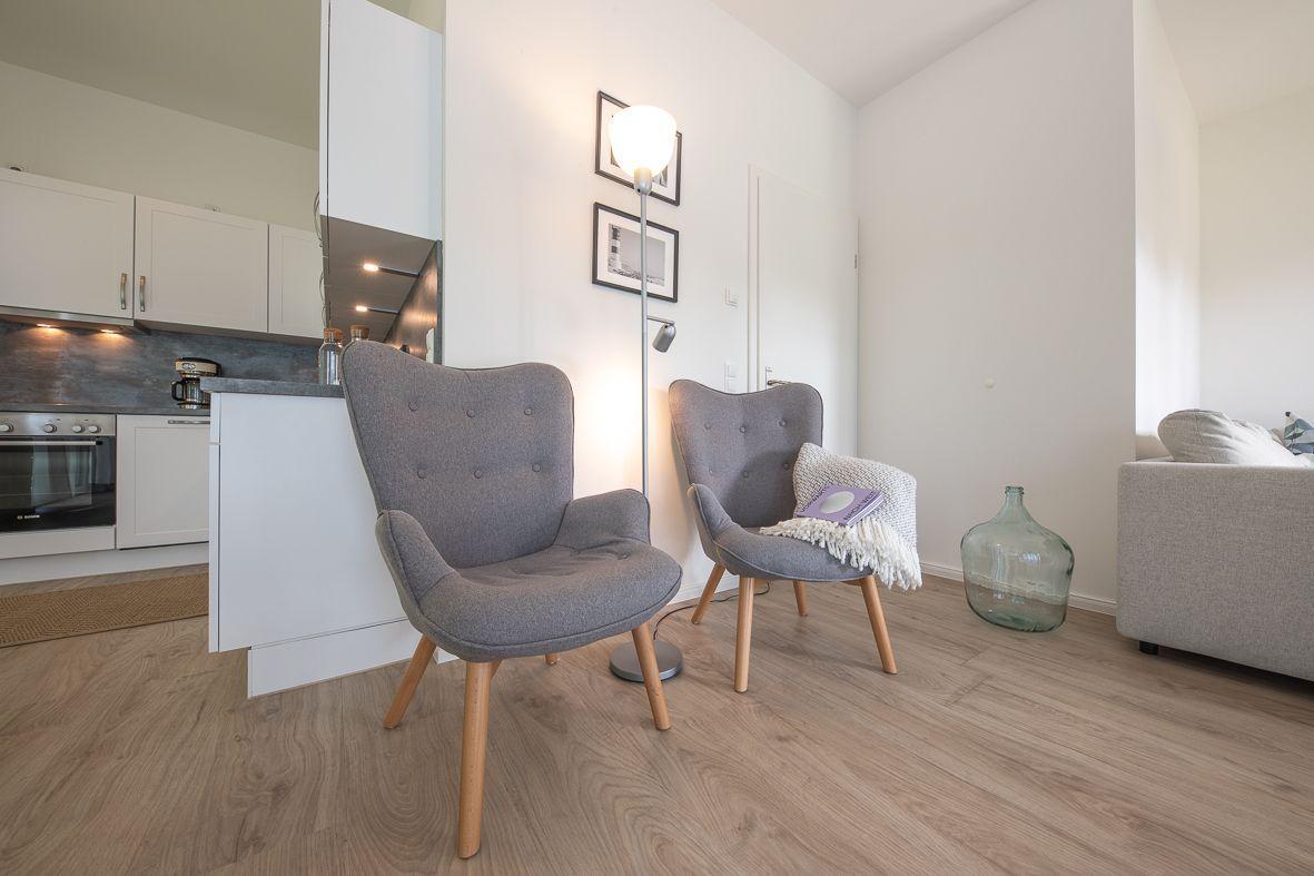 Wohnraum mit Sofa, Spielteppich und Babybett. Deckenleuchte und Schrank sind vorhanden.