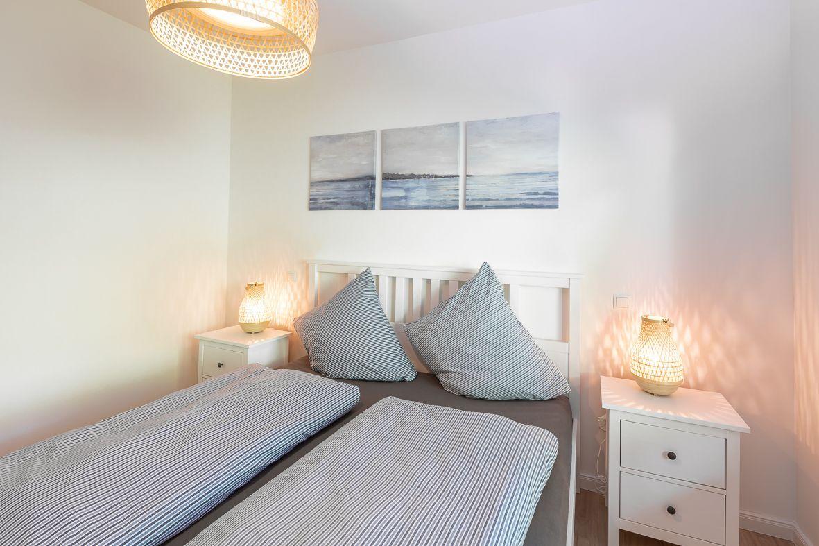 Schlafzimmer mit Bett, Kleiderschrank und Ballbad. Deckenleuchte und Fenster sichtbar.