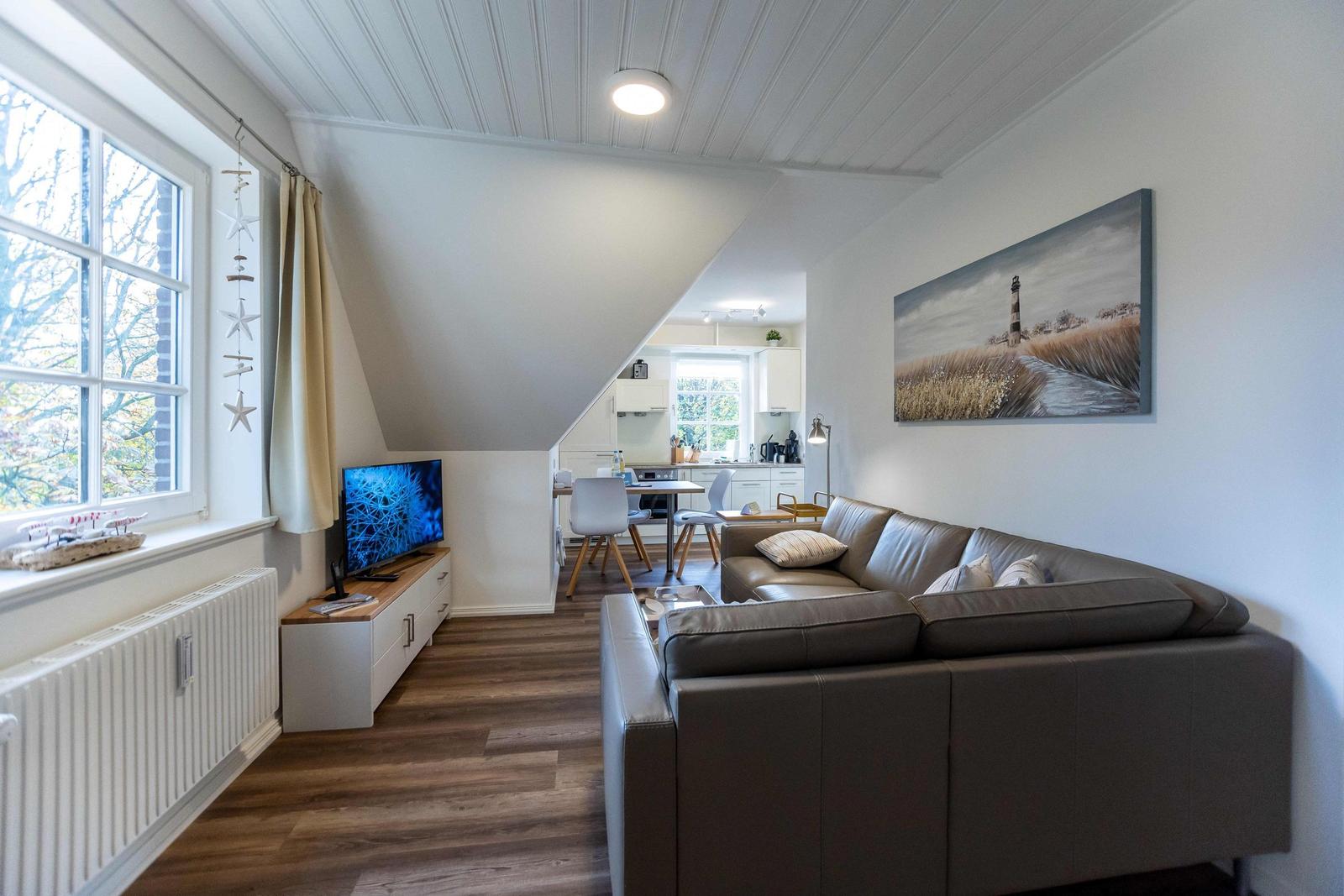 Ein Schlafzimmer mit Dachschräge, Bett, gelber Sitzgelegenheit und Kleiderschränken.