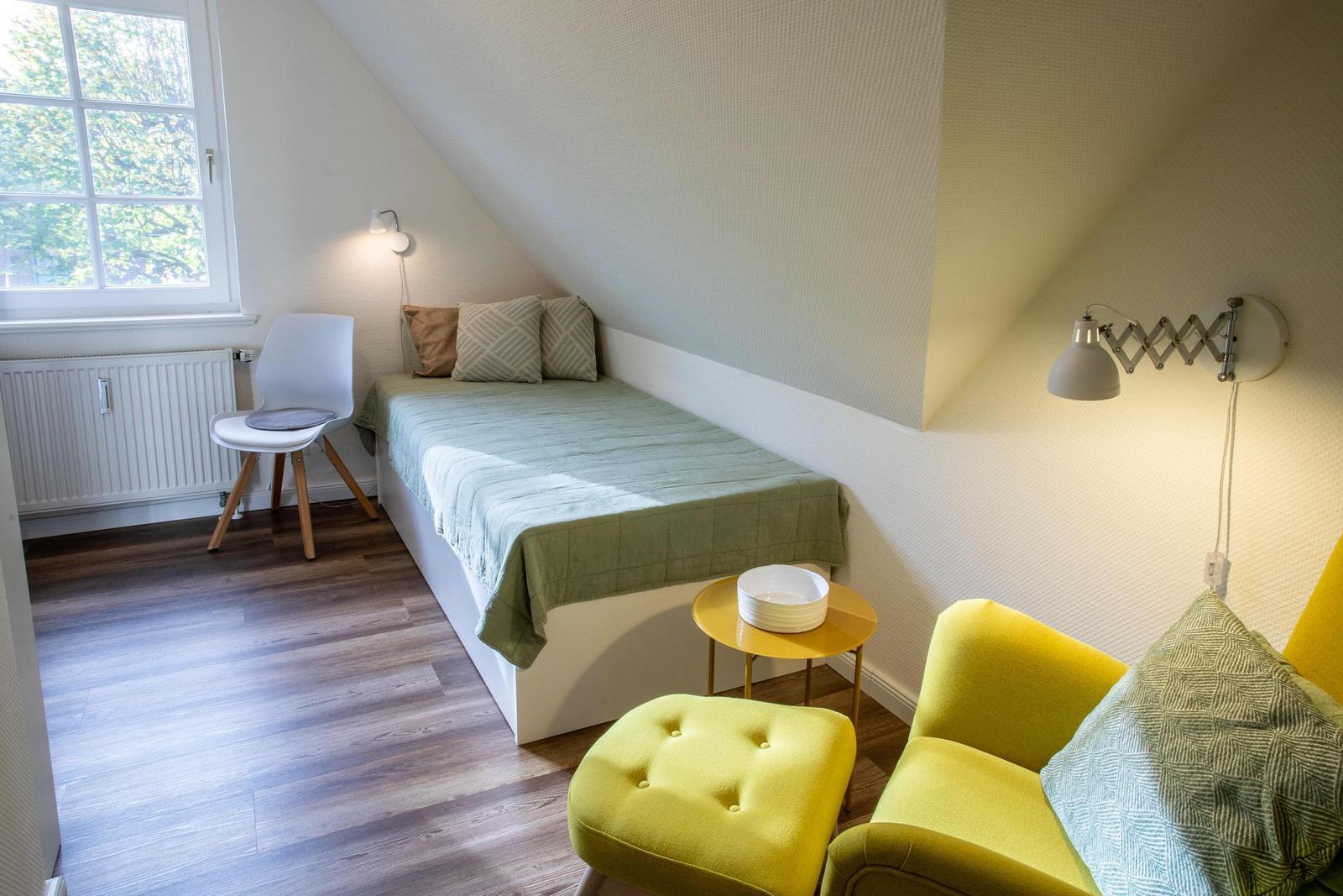 Schlafzimmer mit Doppelbett, Nachttischen und Bad im Hintergrund.