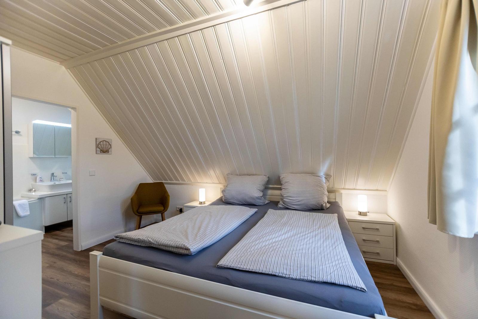 Schlafzimmer mit Dachschrägen, Bett, Fenster und Tür