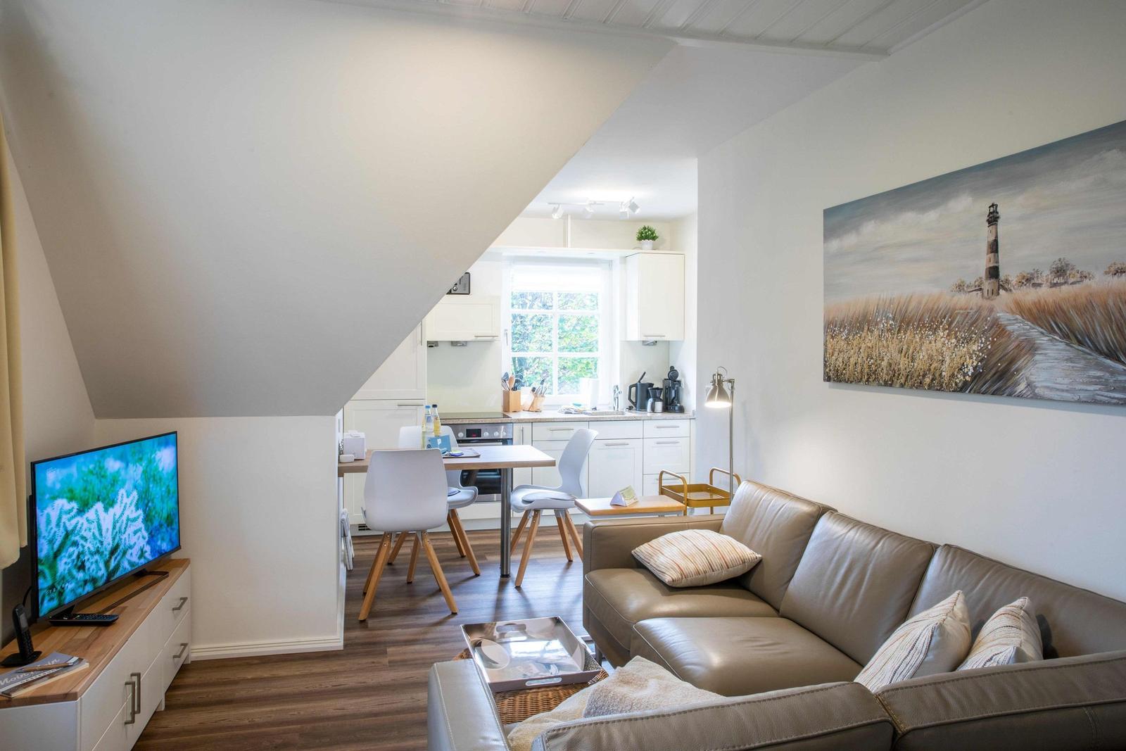 Wohnzimmer mit TV, Sofa, Fenster und Schrank. Dachschräge und Holzboden.