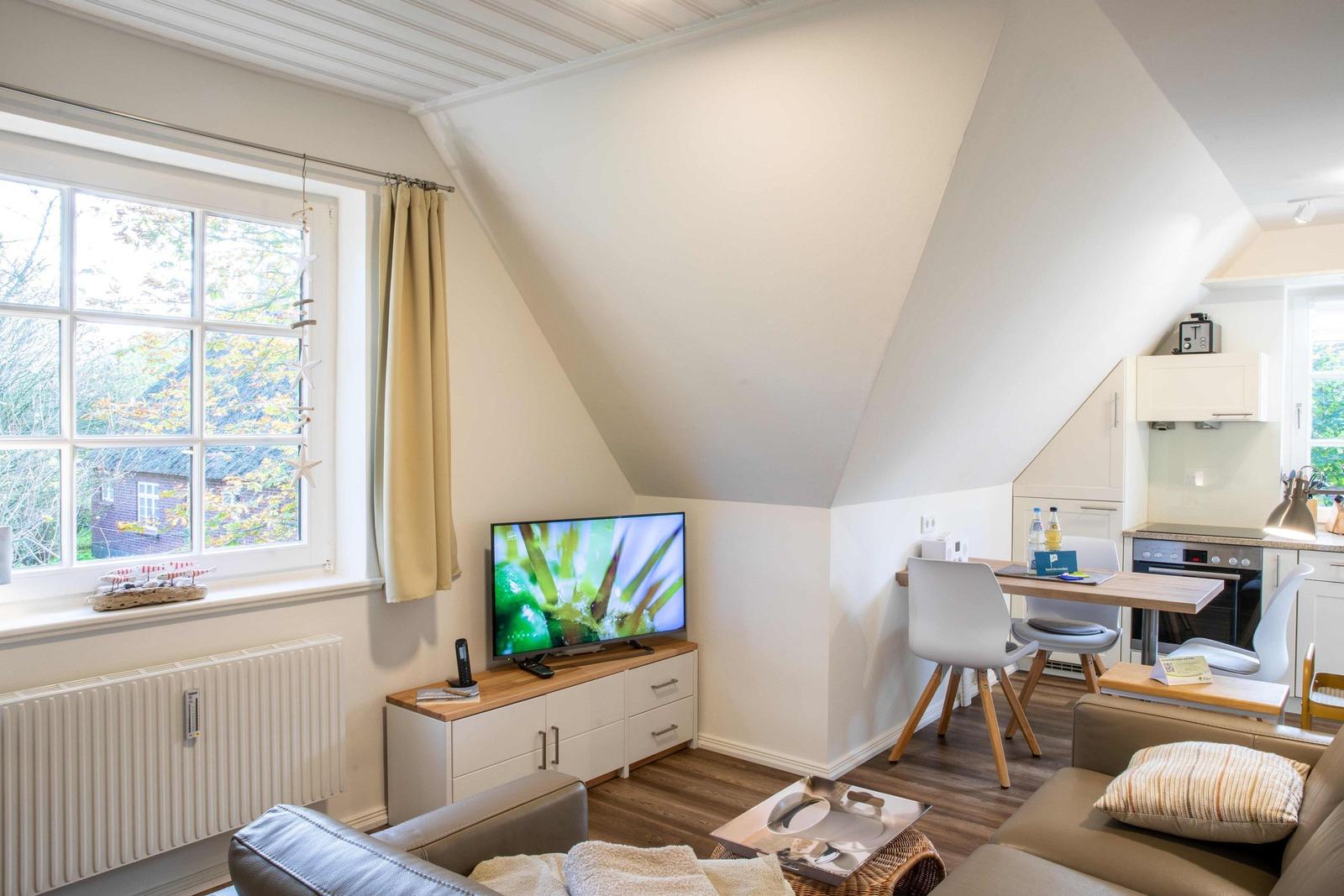 Wohnzimmer mit Sofa, Wandbildern und Blick in Schlafzimmer