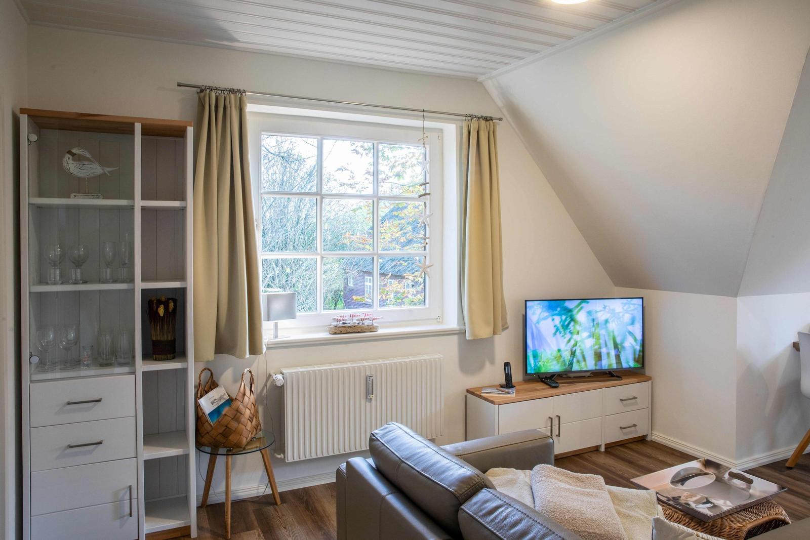 Wohnzimmer mit Sofa, Wandbildern und Blick in Schlafzimmer