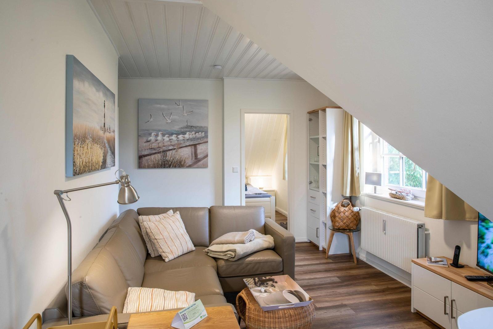 Zimmer mit Doppelbett, Fenster, gelber Sitzgelegenheit und Wandlampe.