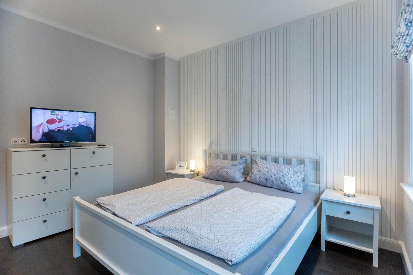 Bedroom with double bed, two nightstands, and a window with a curtain.