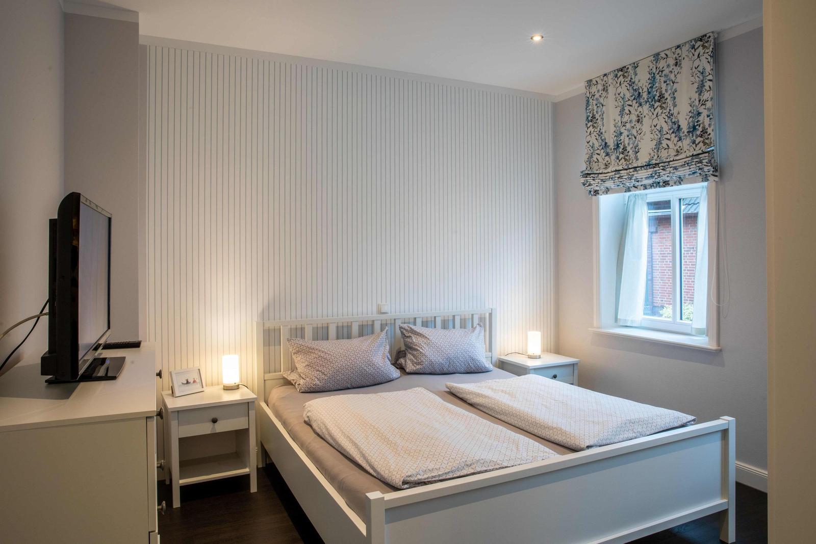 Bedroom with bed, desk, and striped wall.