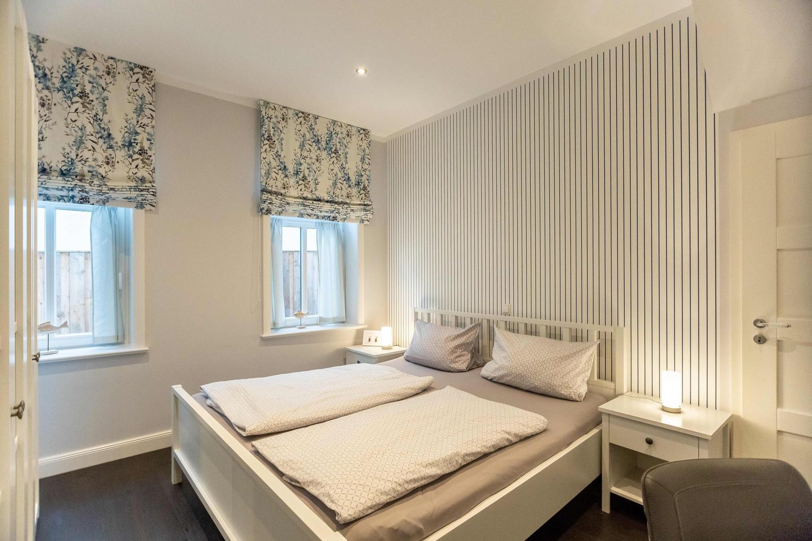 Bedroom with double bed, nightstand, desk, and window.