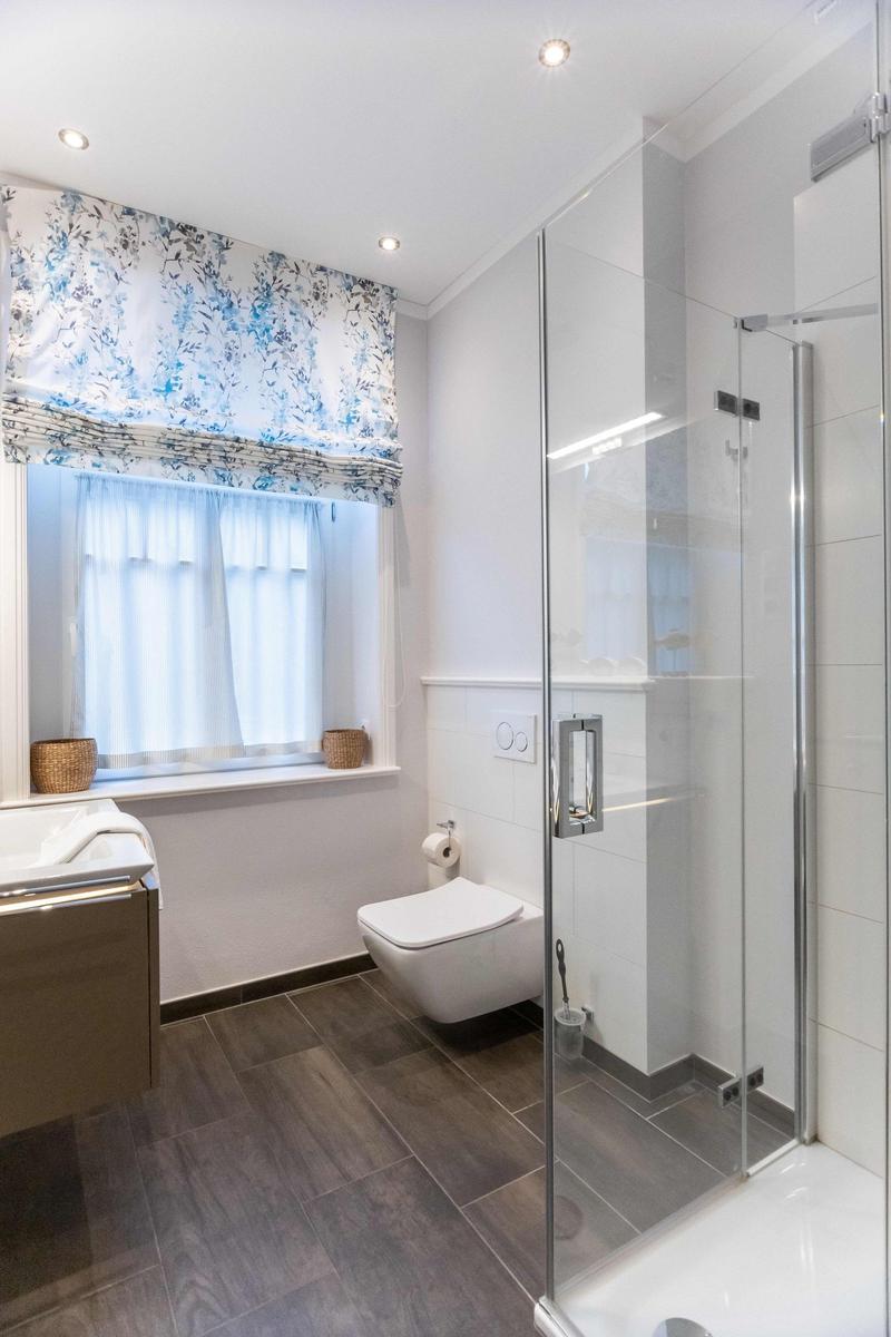 Bathroom with sink, mirror, window, and toilet.