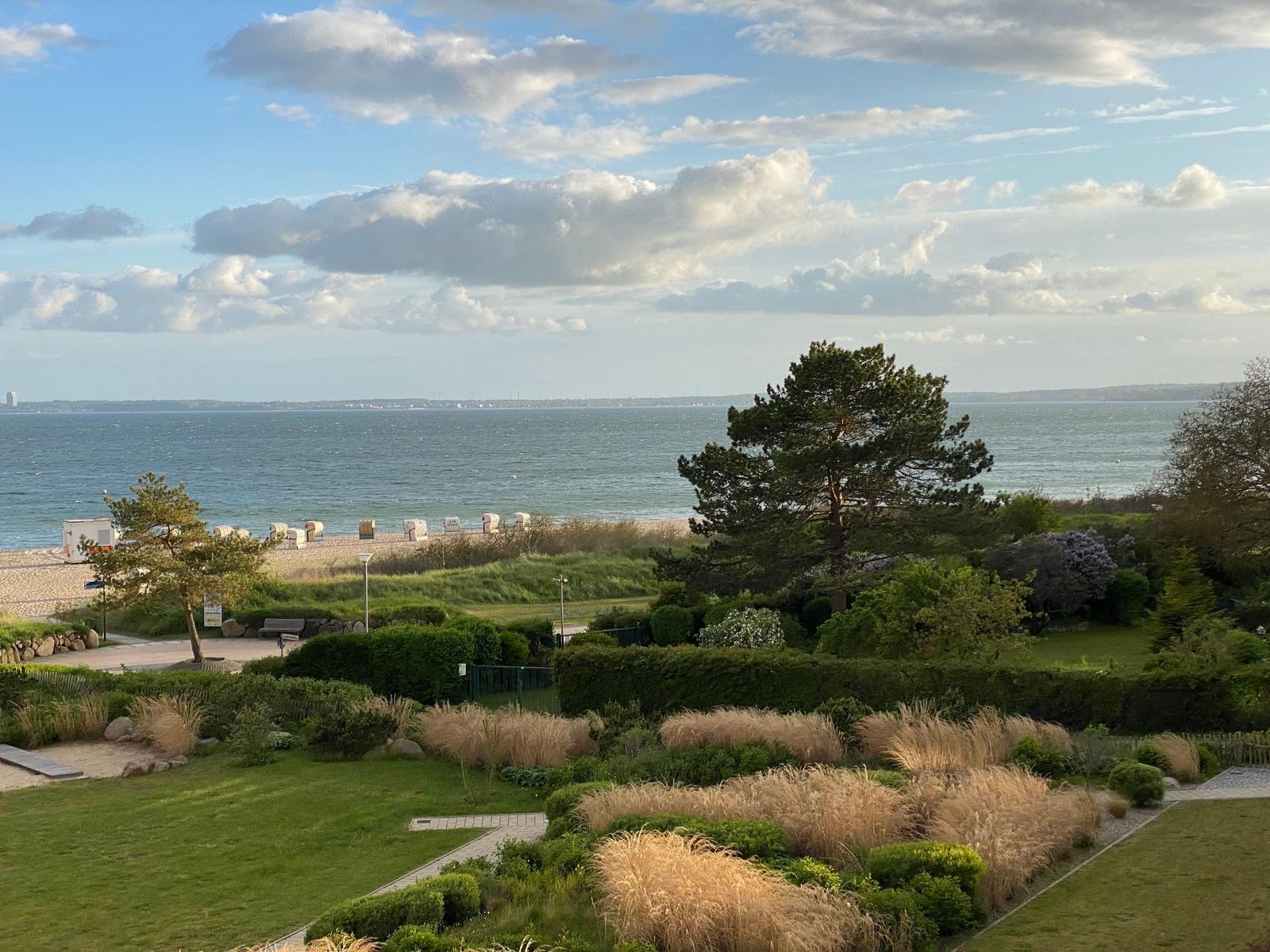 Blick auf Strand, See und Garten mit Bäumen und Beerensträuchern.