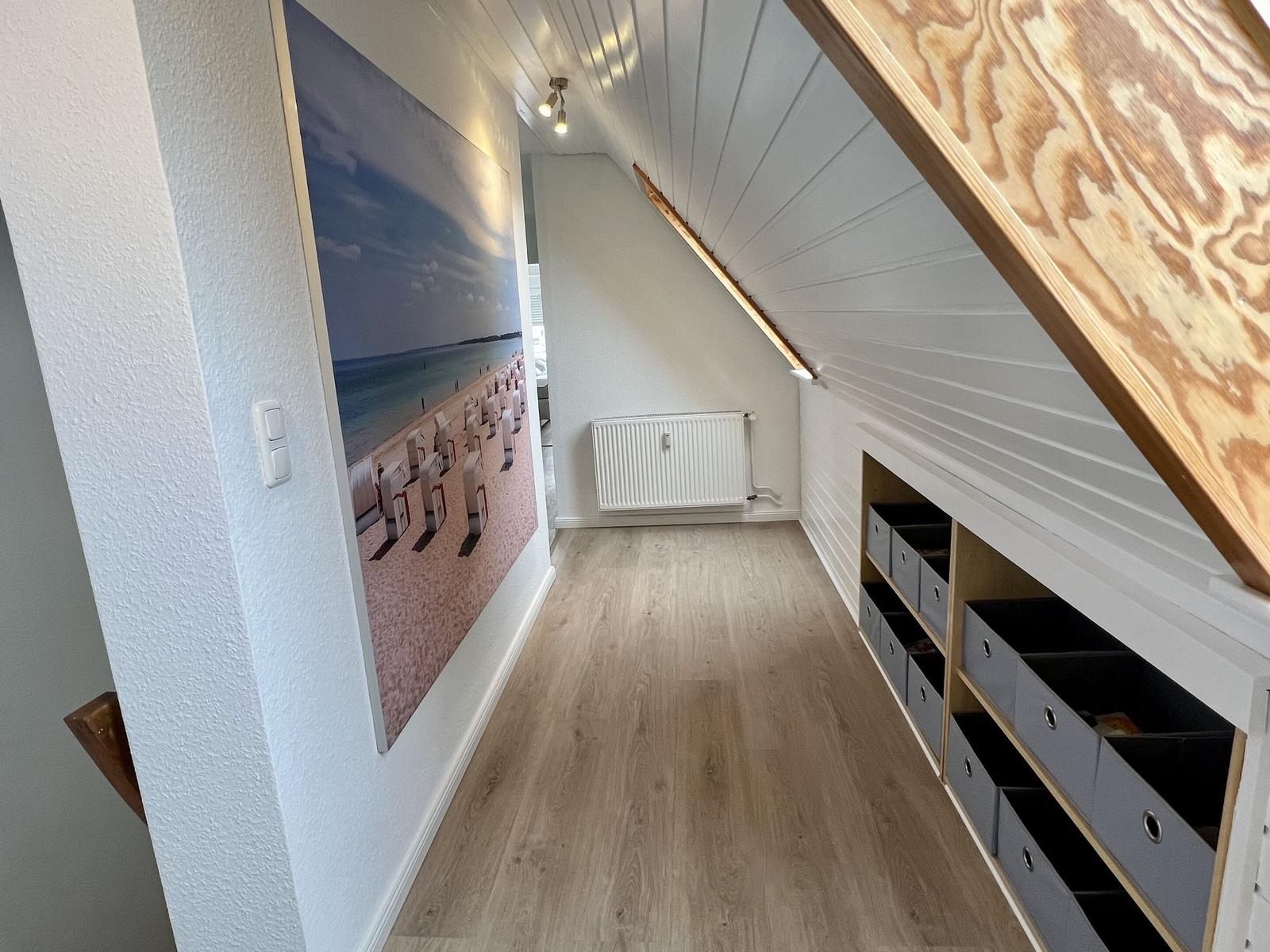 Schlafzimmer mit Bett, Wandbildern und Dachfenster mit Baumdarstellung.