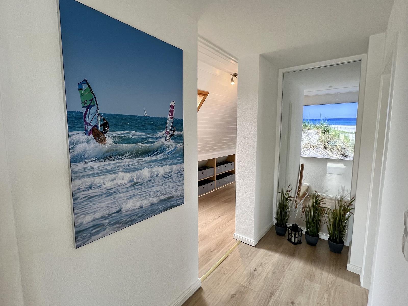 Schlafzimmer mit Dachfenster, Bett, Wandbildern und Holzboden.