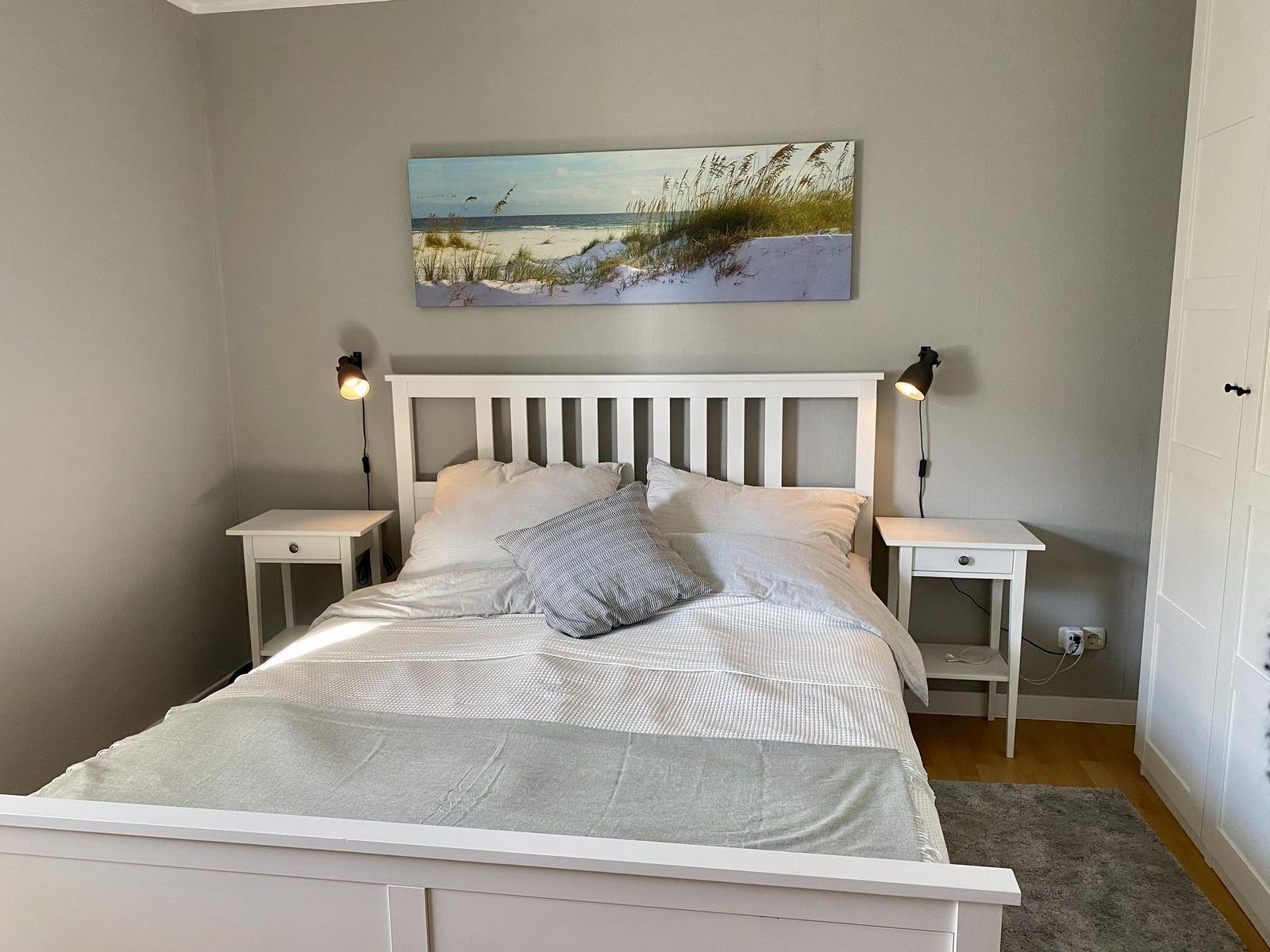 Schlafzimmer mit Bett, Spiegelschrank und Fenster mit Blick nach draußen.