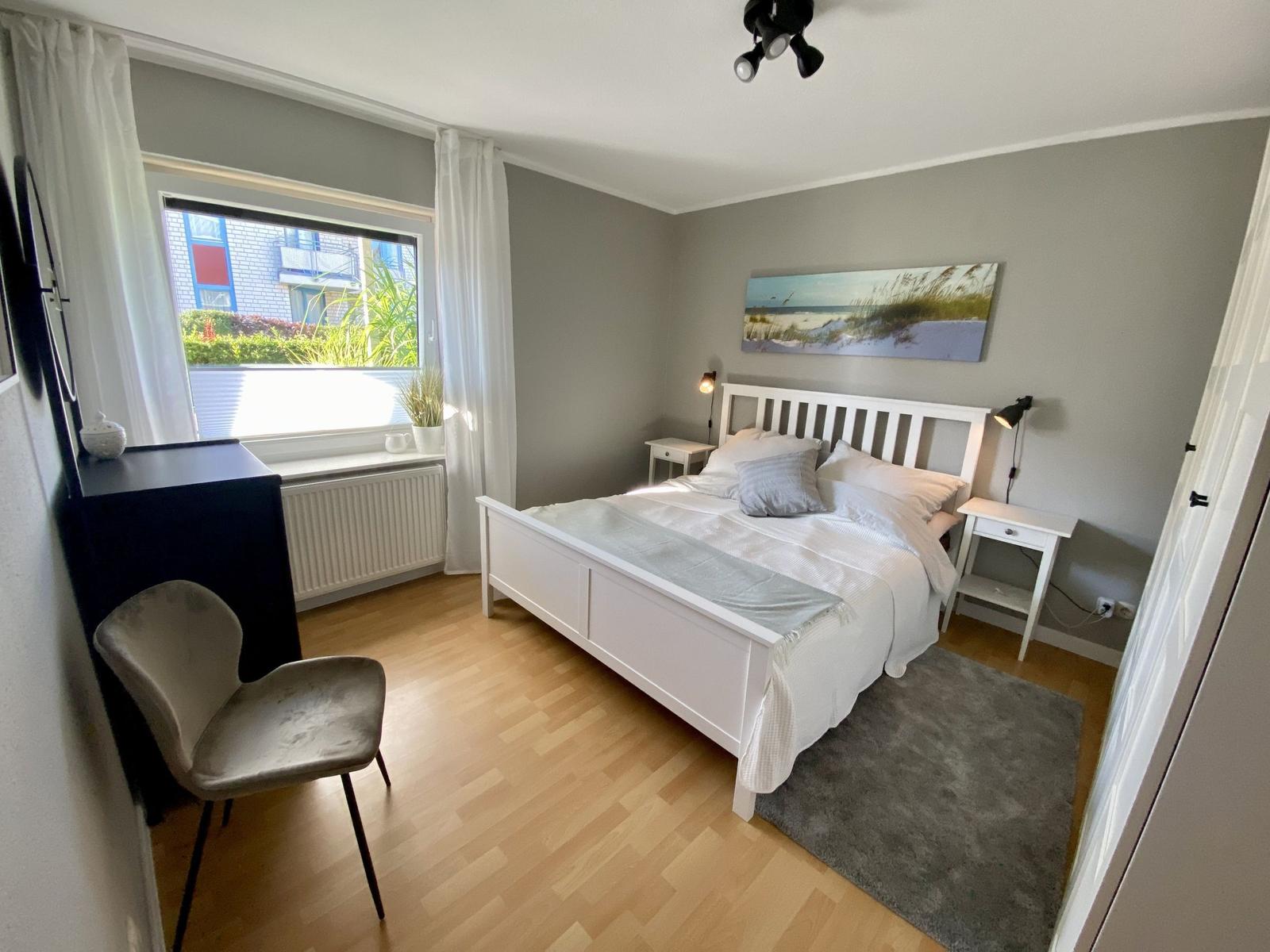 Schlafzimmer mit Bett, Kleiderschrank und Wandbildern.
