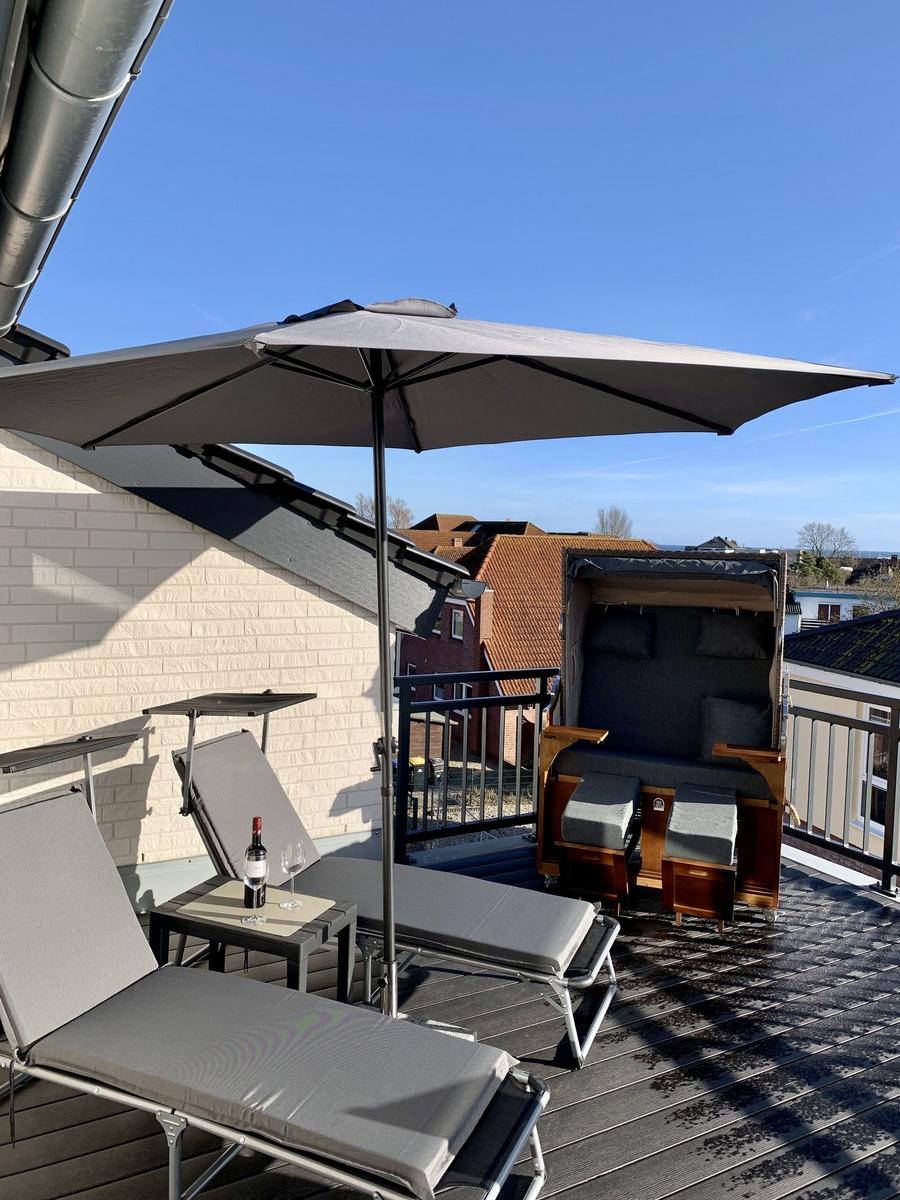 Holzliege mit Schutzdach und Kissen auf Terrasse