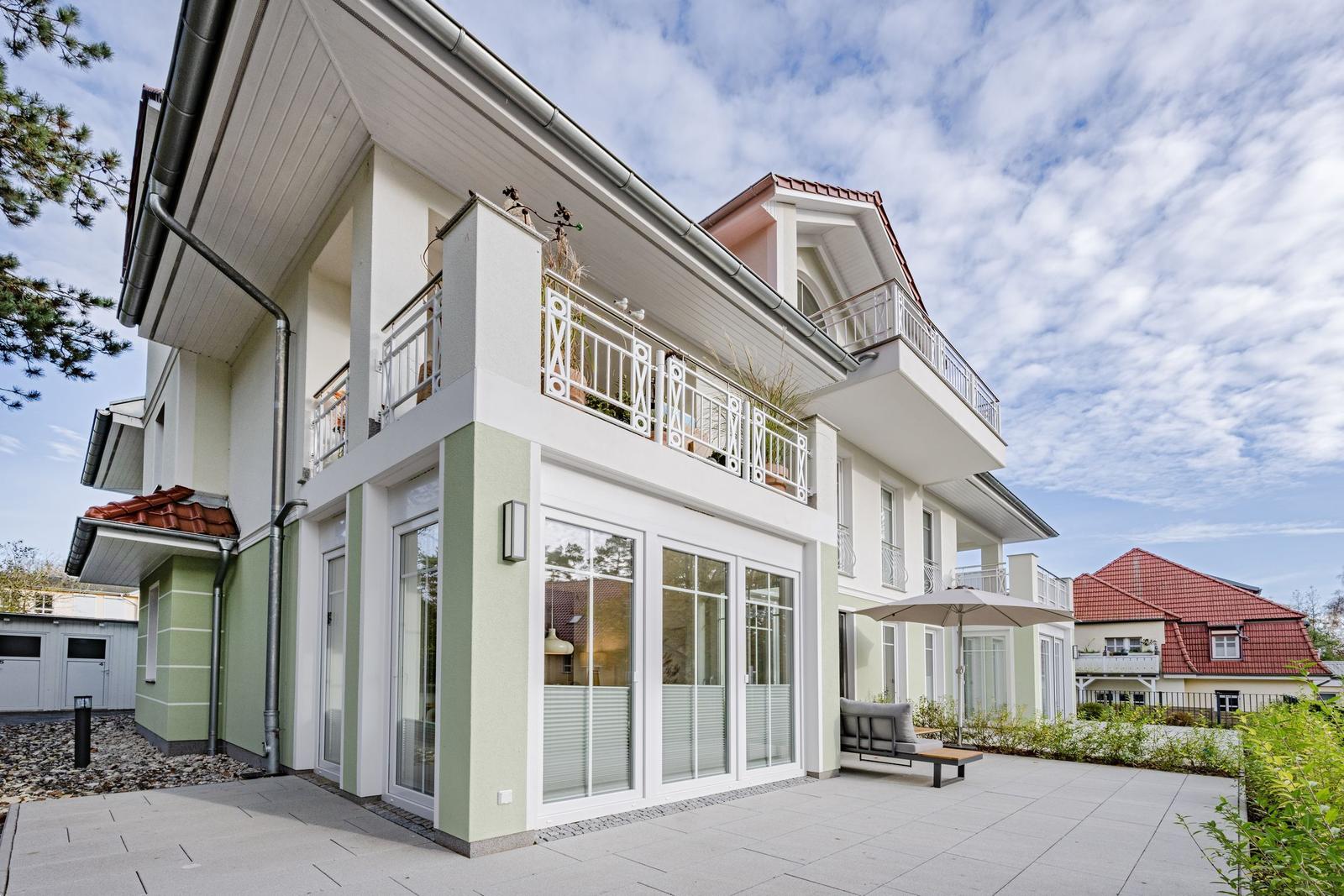 Modernes zweistöckiges Haus mit grün-weißer Fassade und rotem Dachziegel