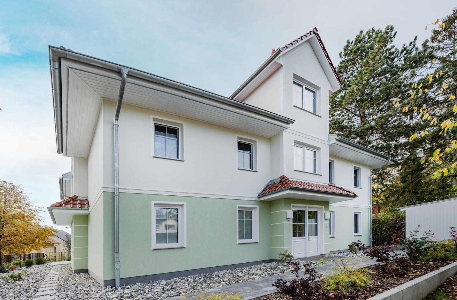 Moderne Villa mit Balkonen und Terrasse unter blauem Himmel.