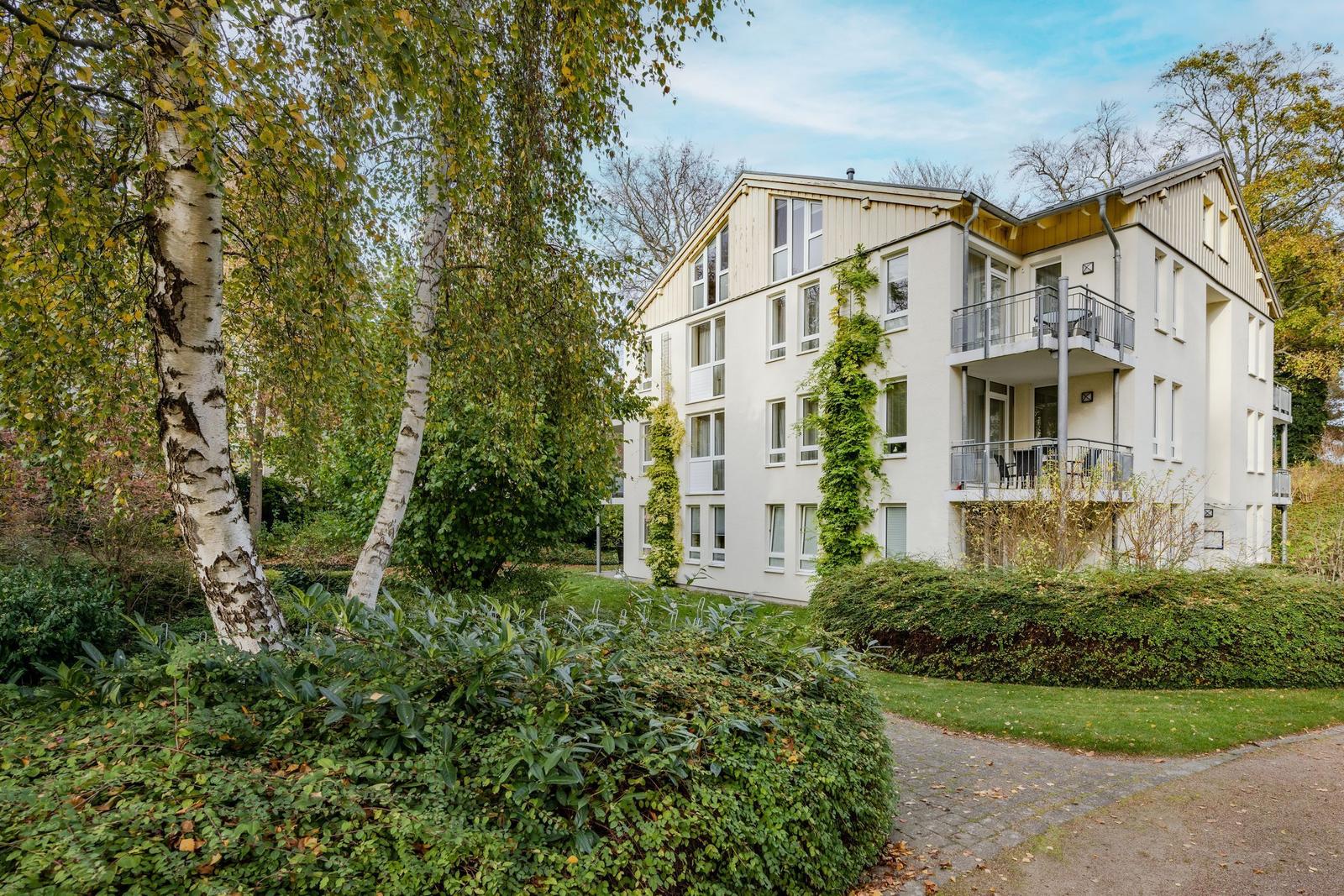 Weitläufiger Park mit Pool und Bäumen neben Strand und Meer