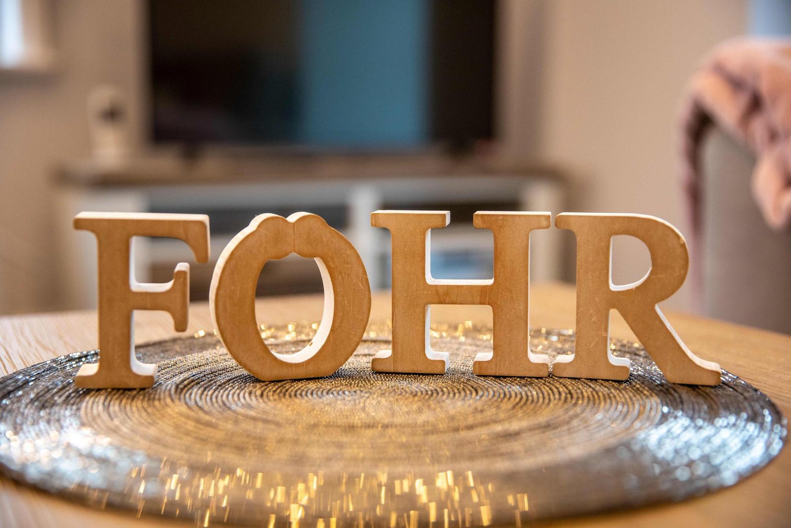 Wohnzimmer mit Sofa und gestreifter Wand. Flur führt in den dahinterliegenden Raum.