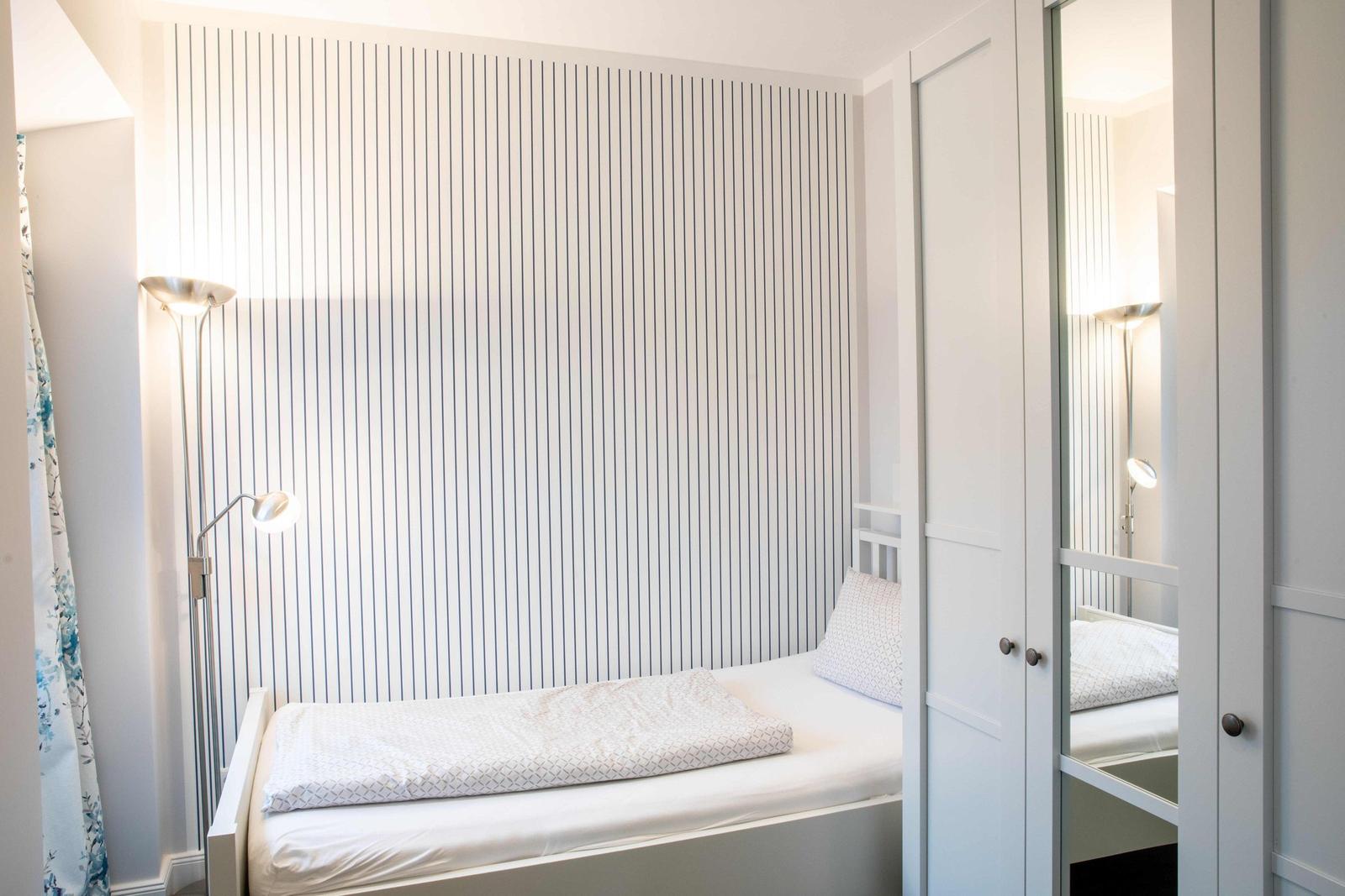 Schlafzimmer mit Doppelbett, Nachttischen und Fenster mit Vorhang.