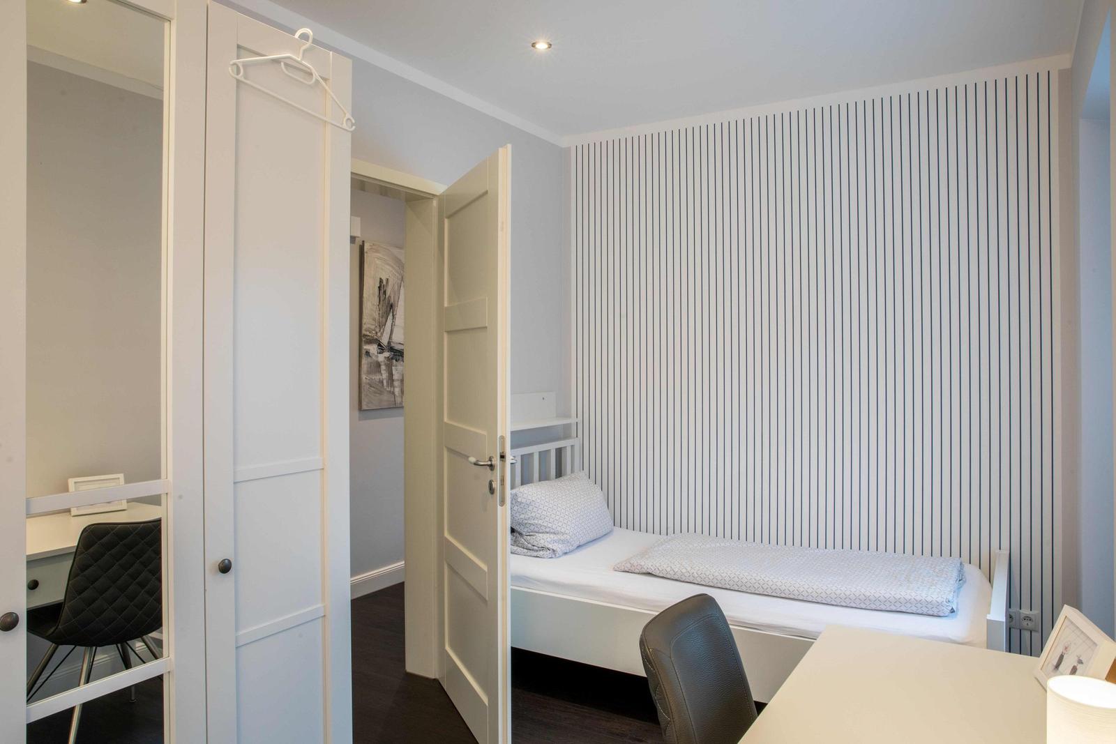 Schlafzimmer mit Bett, Kleiderschrank und Fernseher auf Schrank.