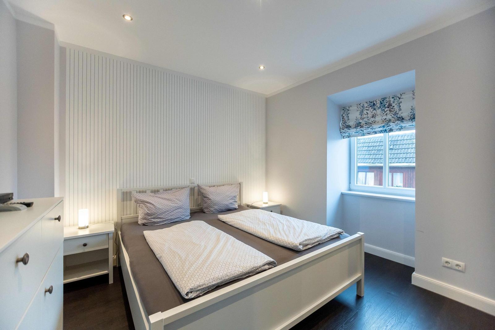 Schlafzimmer mit Doppelbett, Nachttischen und Fernseher auf Schrank.