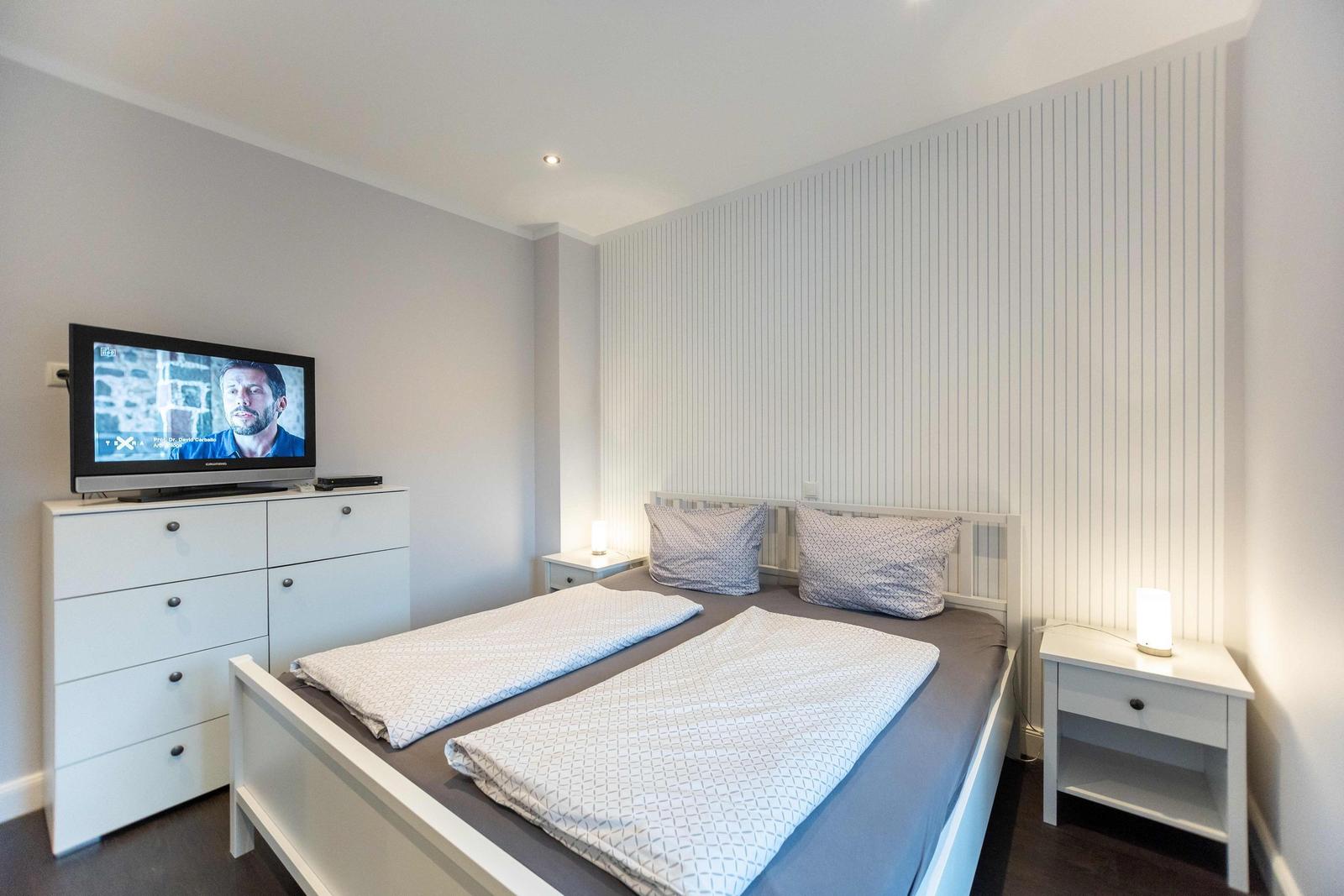 Schlafzimmer mit Doppelbett, zwei Nachttischen und Fenster mit Rollladen.