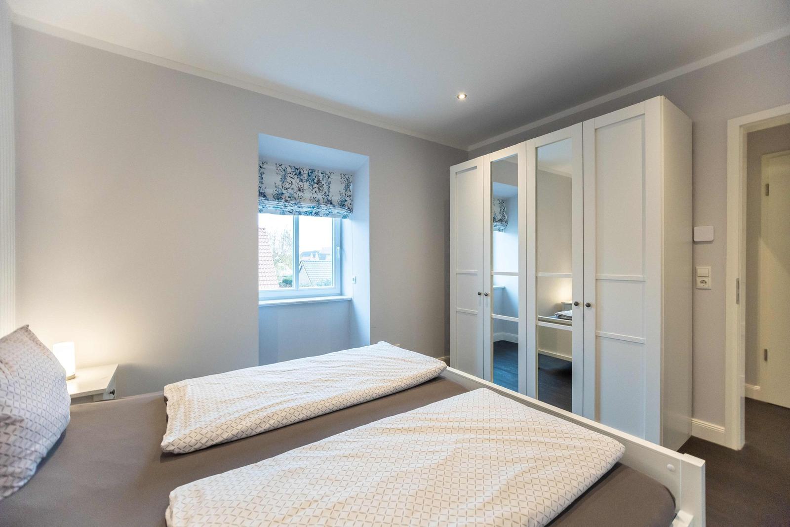 Schlafzimmer mit Bett, Nachttisch und Fernseher auf Schrank.