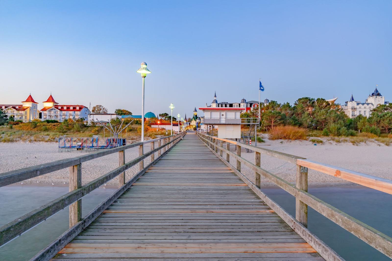 Holzbrücke führt zum Strand mit Hotels im Hintergrund.
